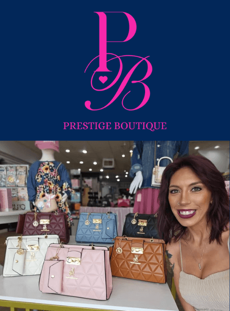 Smiling woman showcasing stylish bags at Prestige Boutique, featuring a variety of colors and designs.