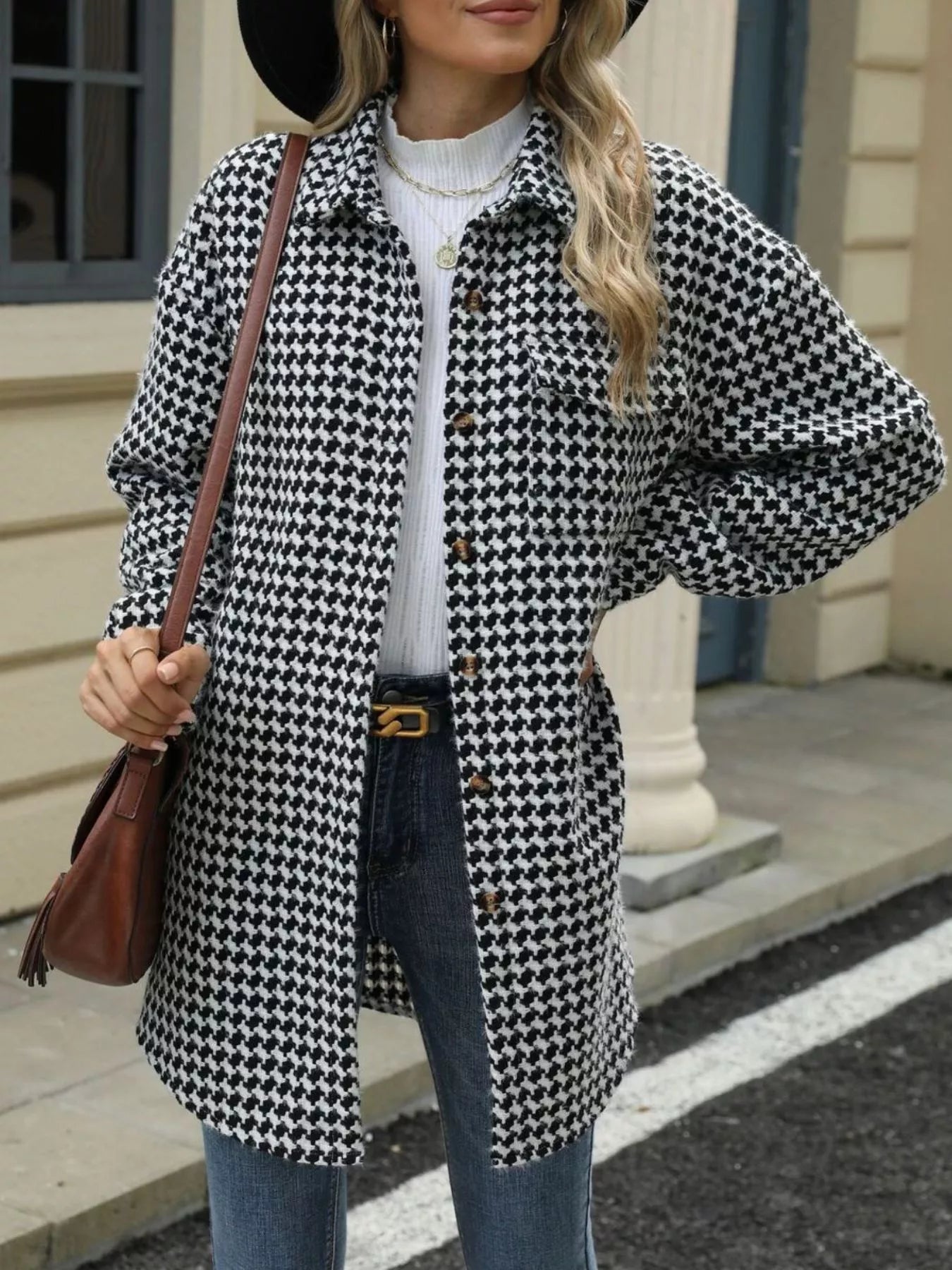 Woman wearing a black and white houndstooth coat with a brown bag.