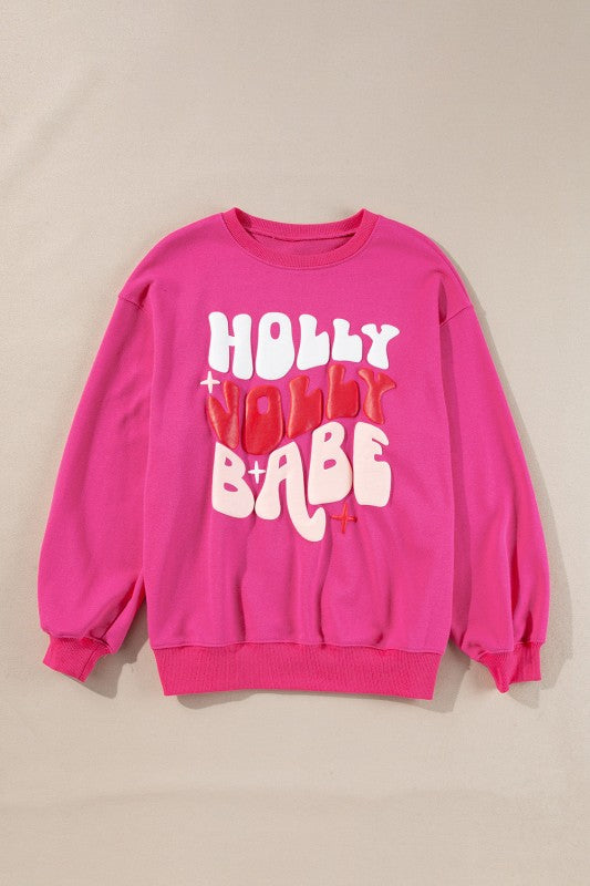Pink sweatshirt with 'Holly Babe' text on a beige background