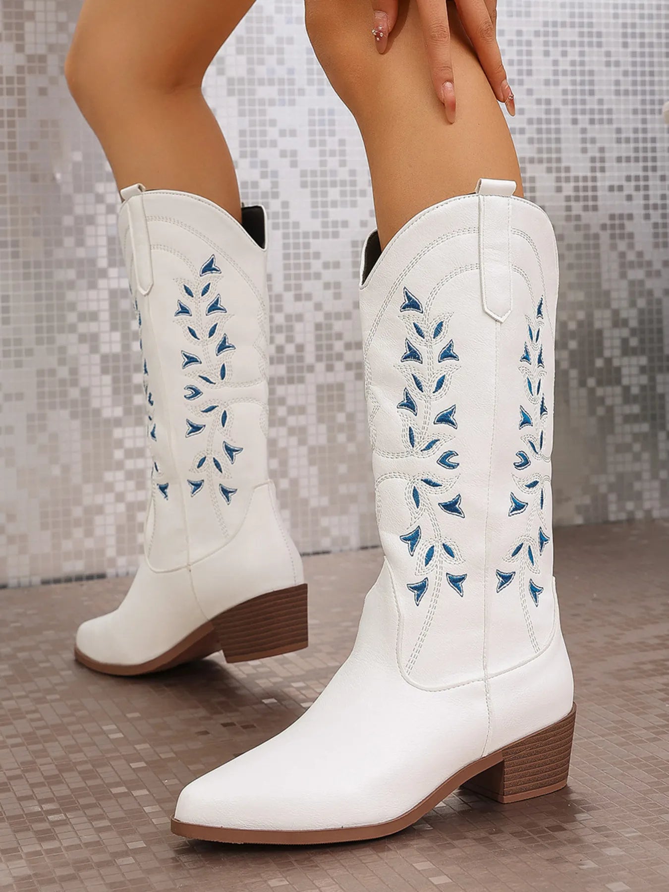 White cowgirl boots with embroidered details, featuring a pointed toe and block heel for stylish comfort.