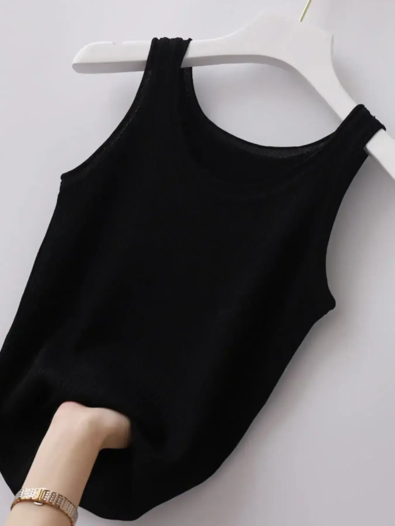 Black tank top on a white hanger against a white background