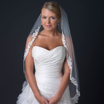 Bridal model wearing a single-layer fingertip-length floral lace veil with rhinestones and elegant wedding gown.