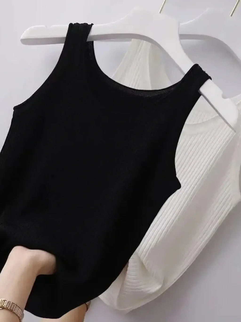 Black tank top on a white hanger against a white background