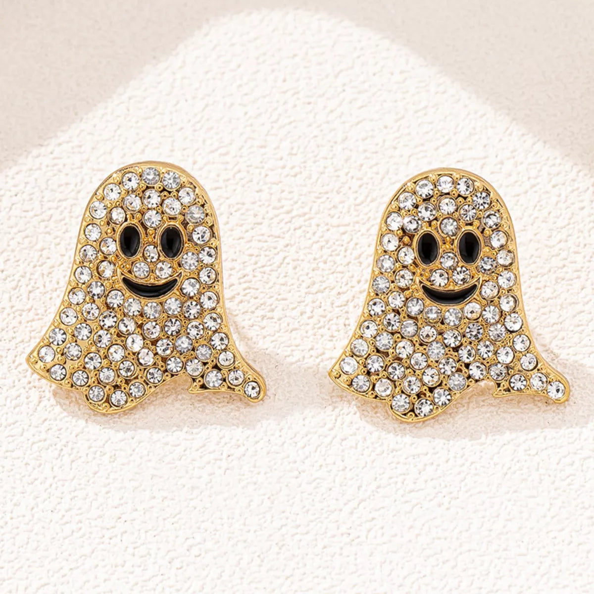 Gold ghost-shaped earrings with rhinestone embellishments on a white background