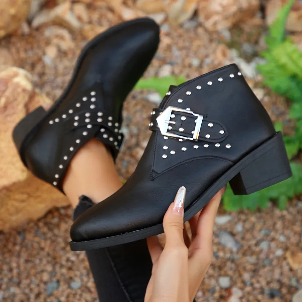 Black studded boots held by a hand with a natural background