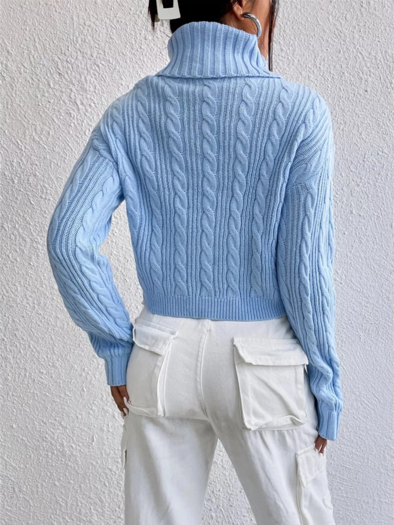 Back view of a woman wearing a Cable-Knit Turtleneck Long Sleeve Sweater in light blue with a stylish silhouette.