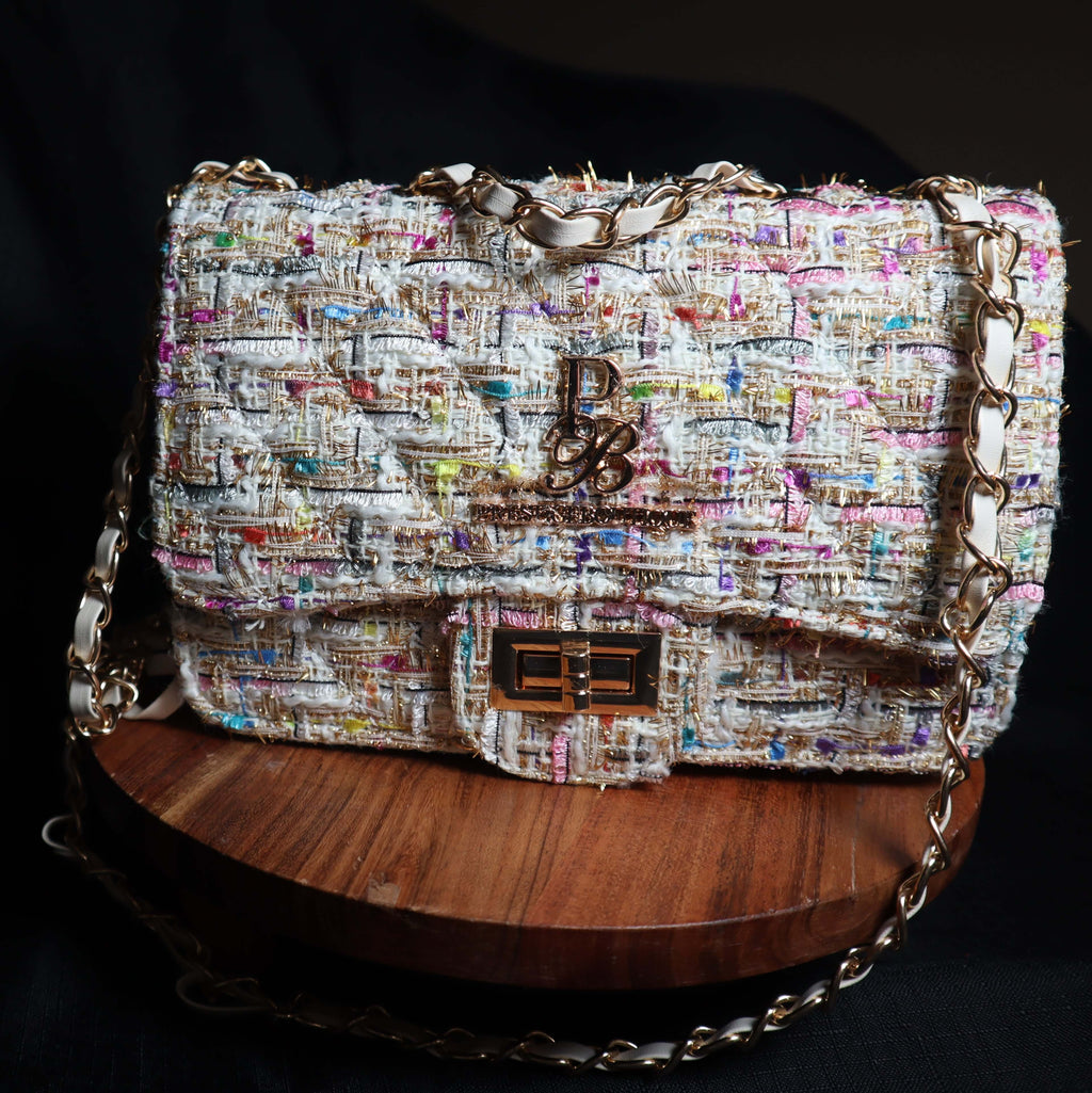 Multicolored textured handbag on a wooden stand with a dark background
