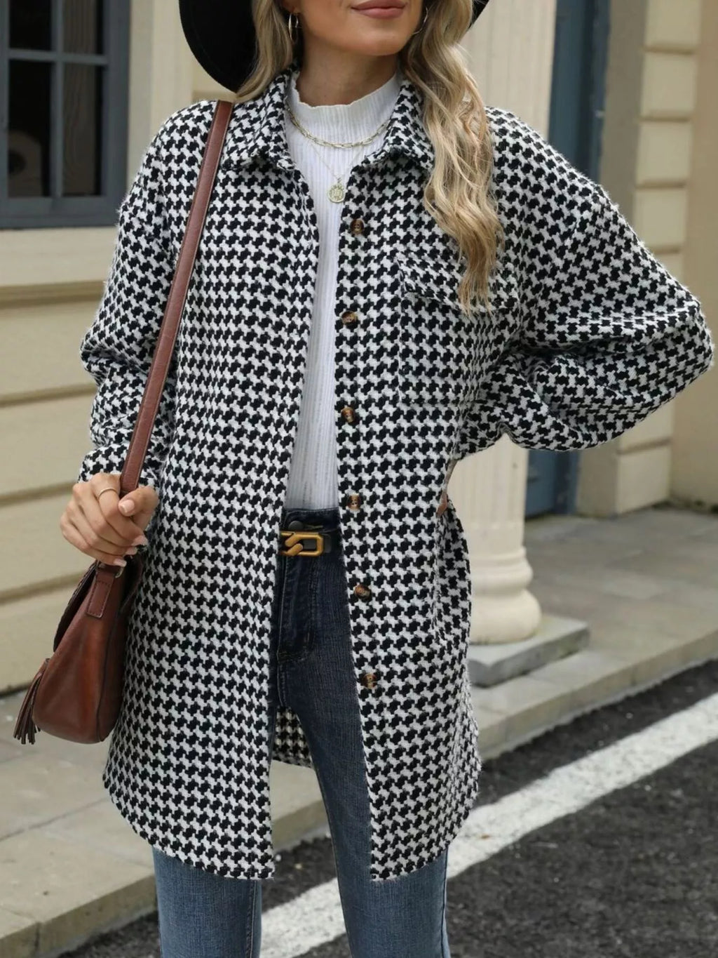 Woman wearing a black and white houndstooth coat with a brown bag.