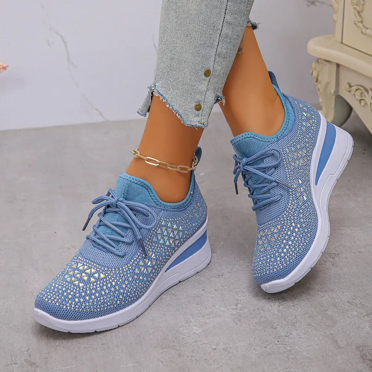 Blue sneakers with white soles worn by a person on a neutral background