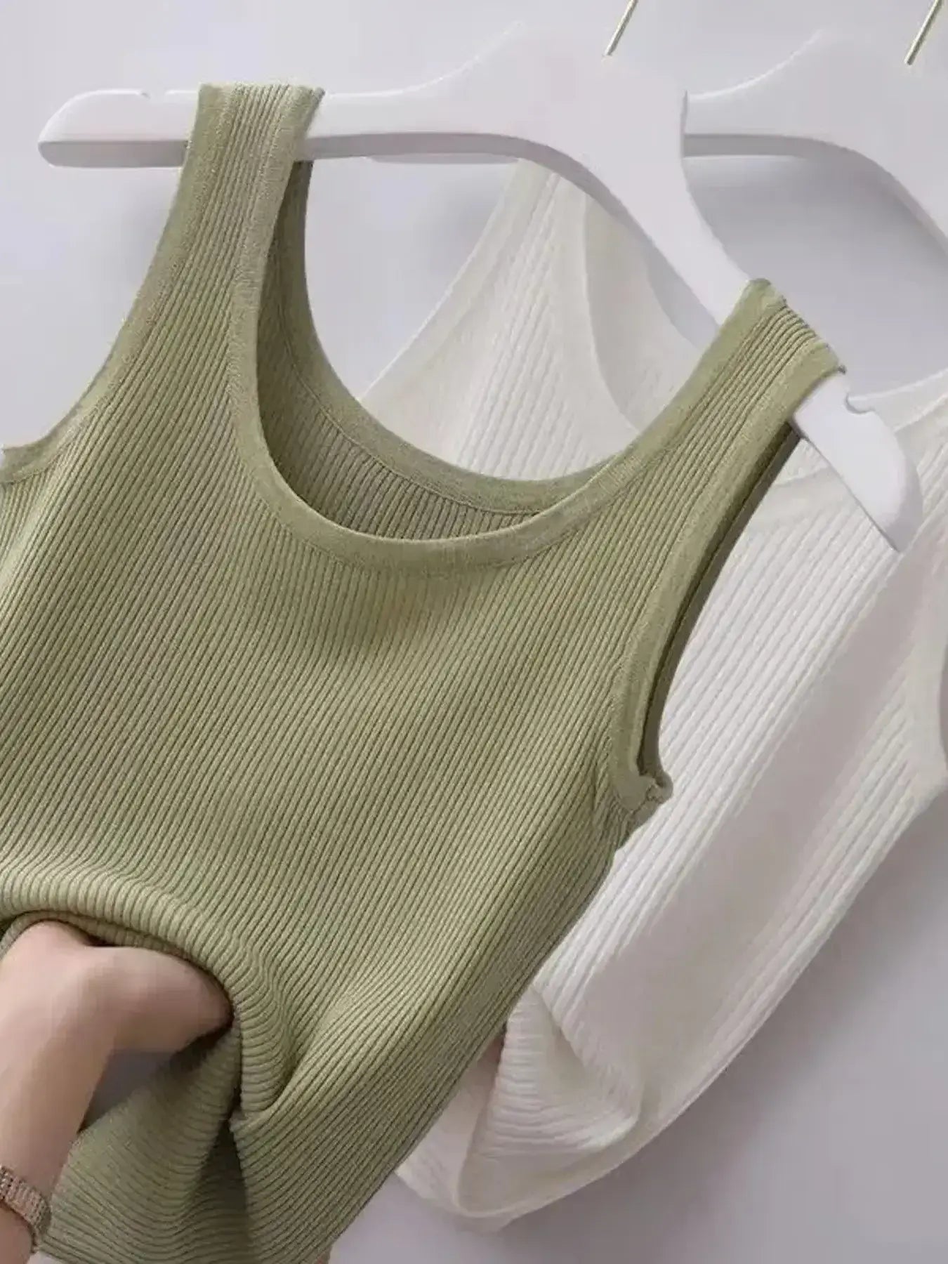 Green ribbed tank top on a white hanger against a white background