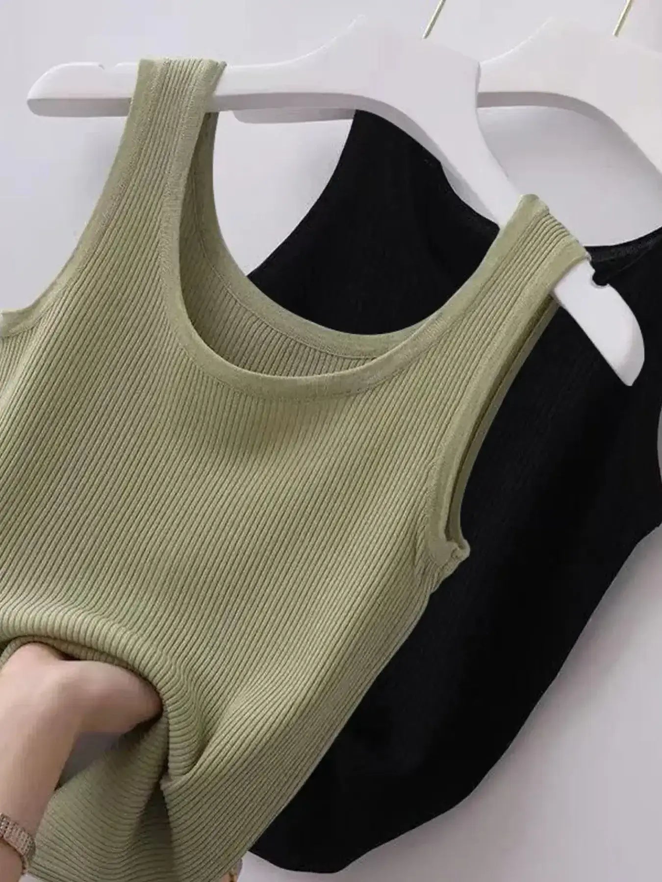 Green tank top on a hanger against a white background