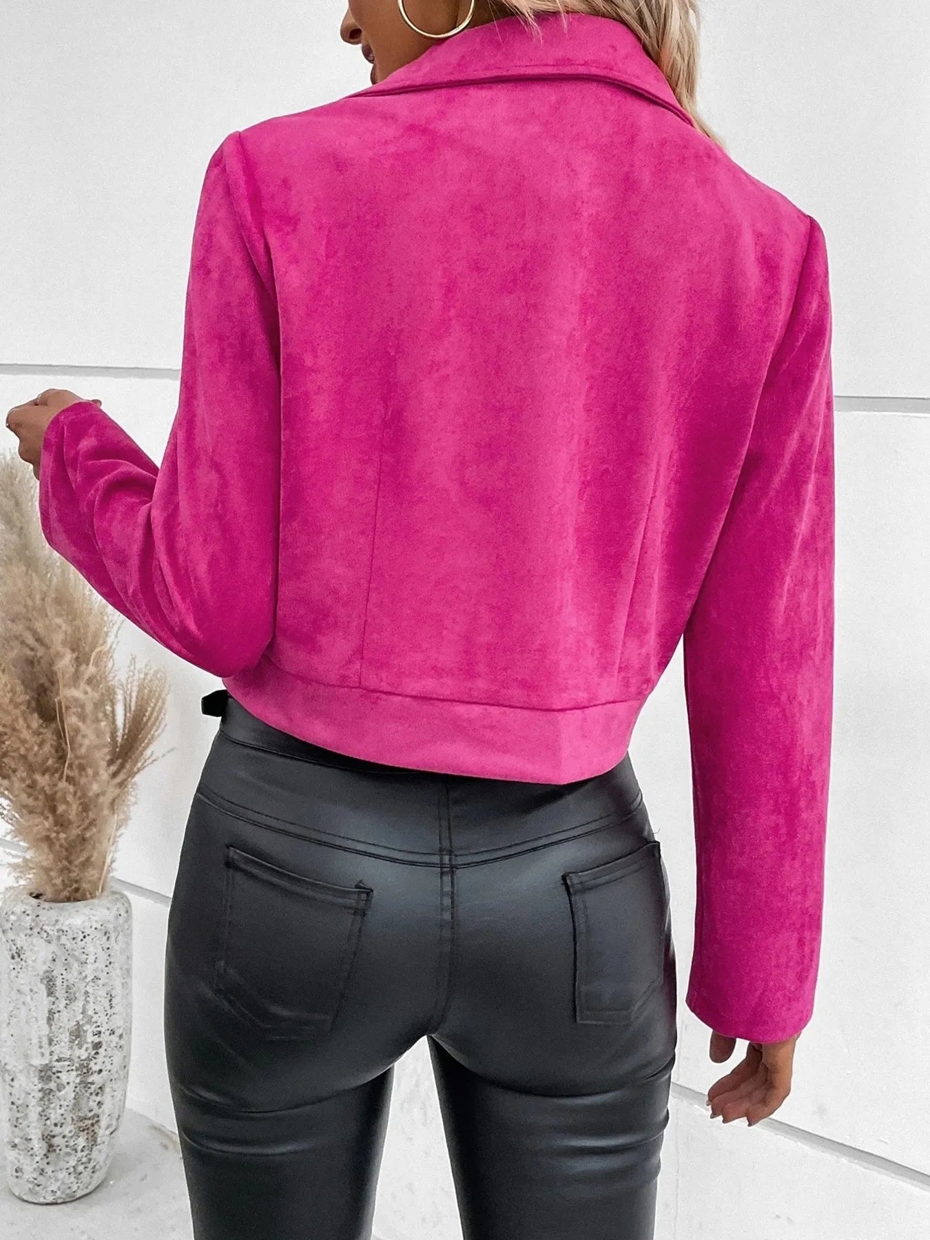 Person wearing a bright pink jacket and black leather pants on a white background