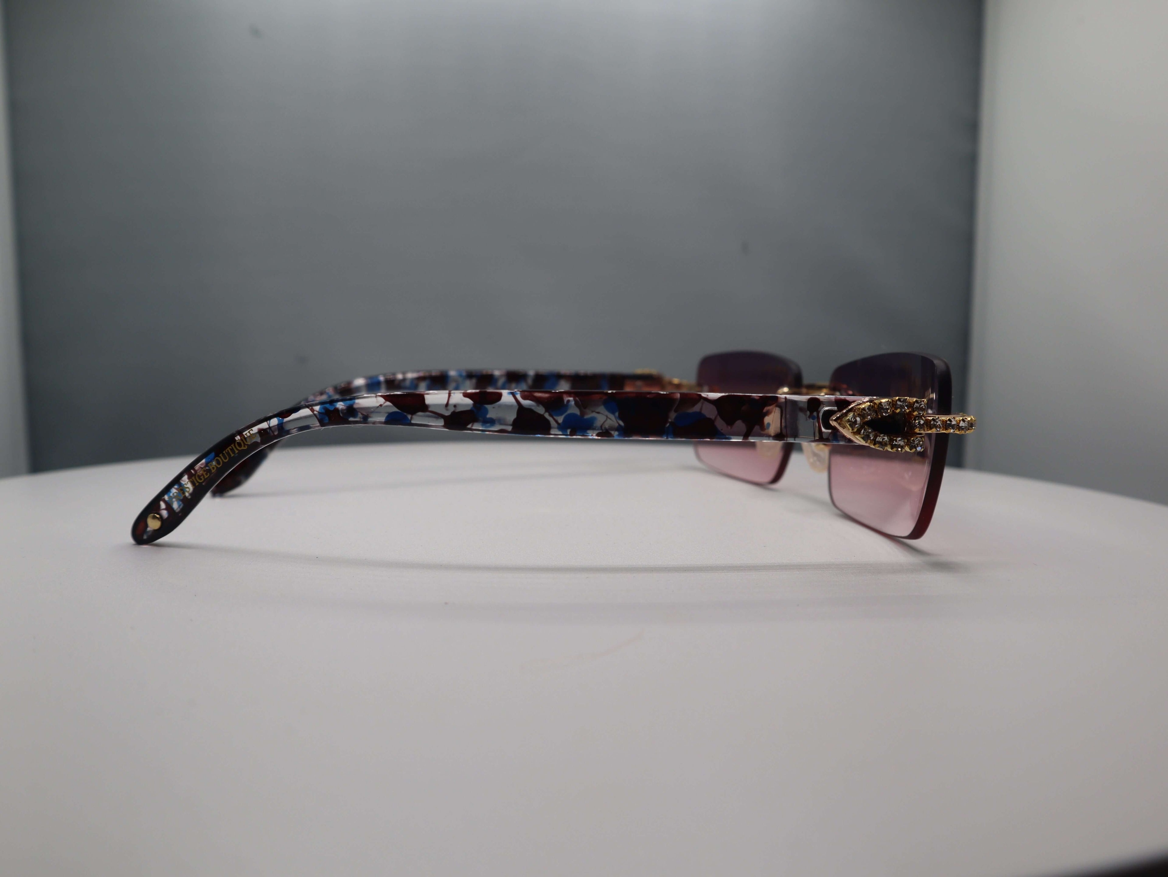 Side view of Prestige Boutique Pink Floral Fashionista sunglasses showcasing black, blue, and gold patterned arms.