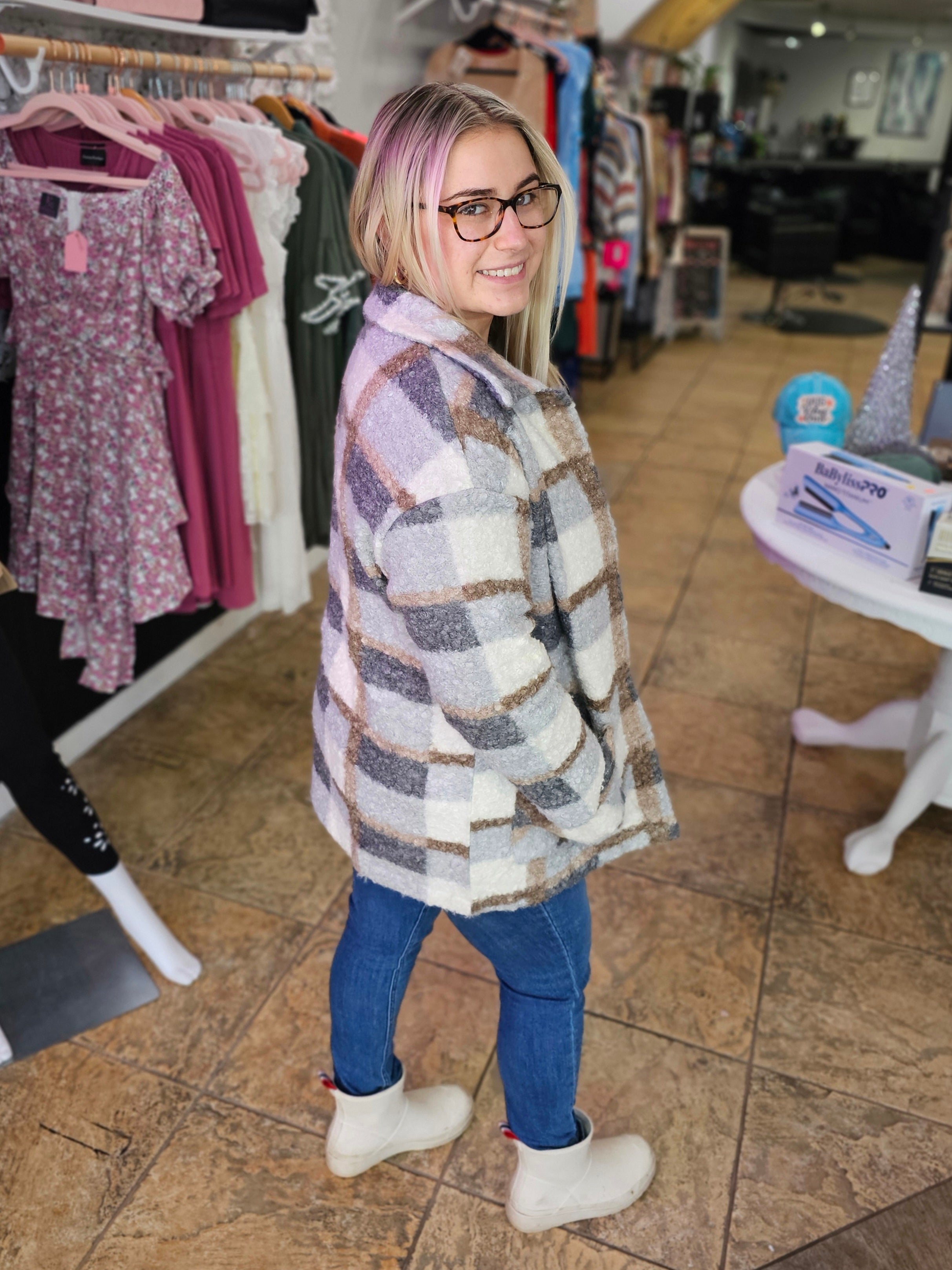 Model wearing a stylish Plaid Woolen Coat with a gray and beige pattern, showcasing its cozy design in a boutique.