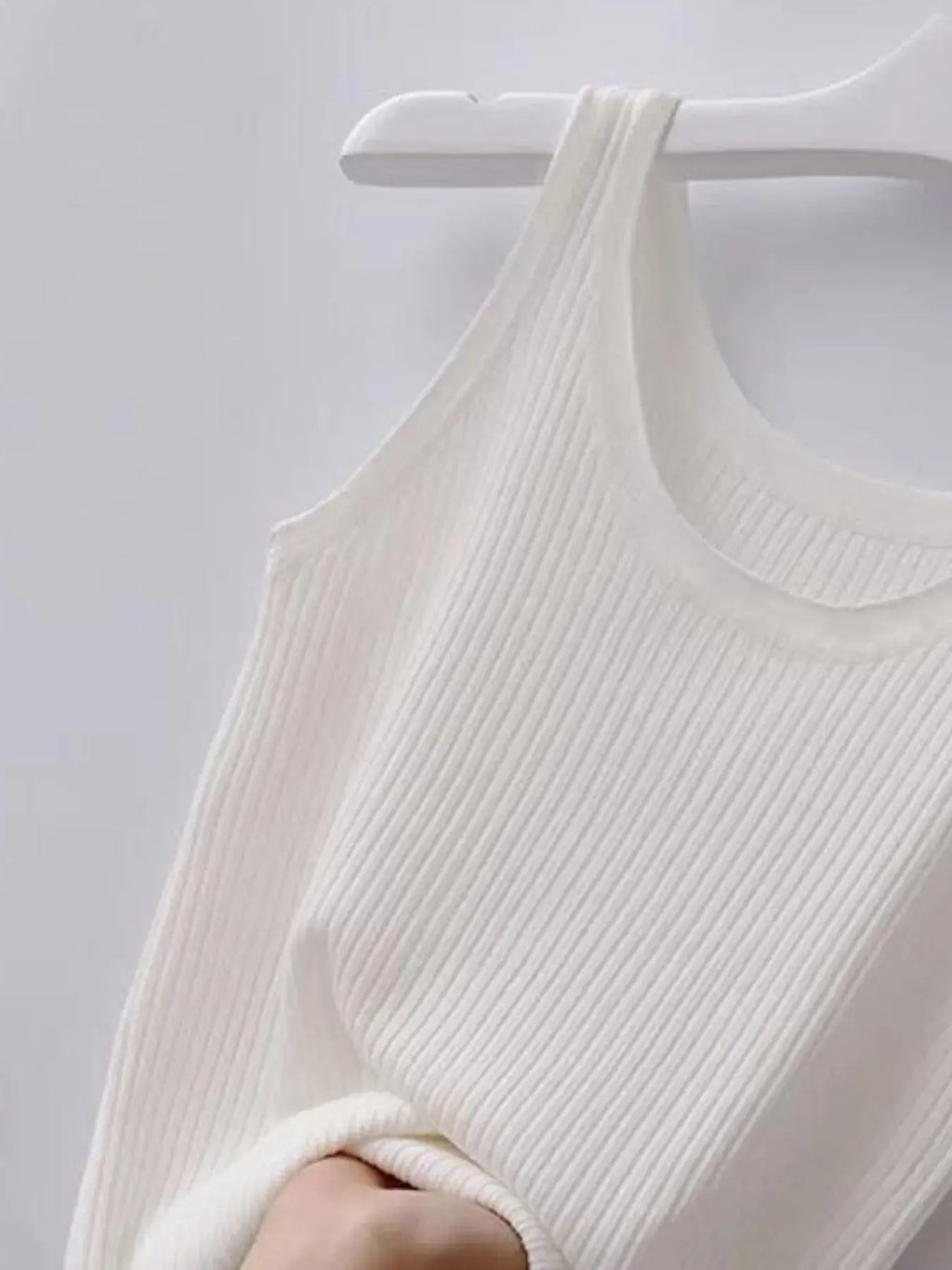White ribbed tank top on a hanger against a light gray background