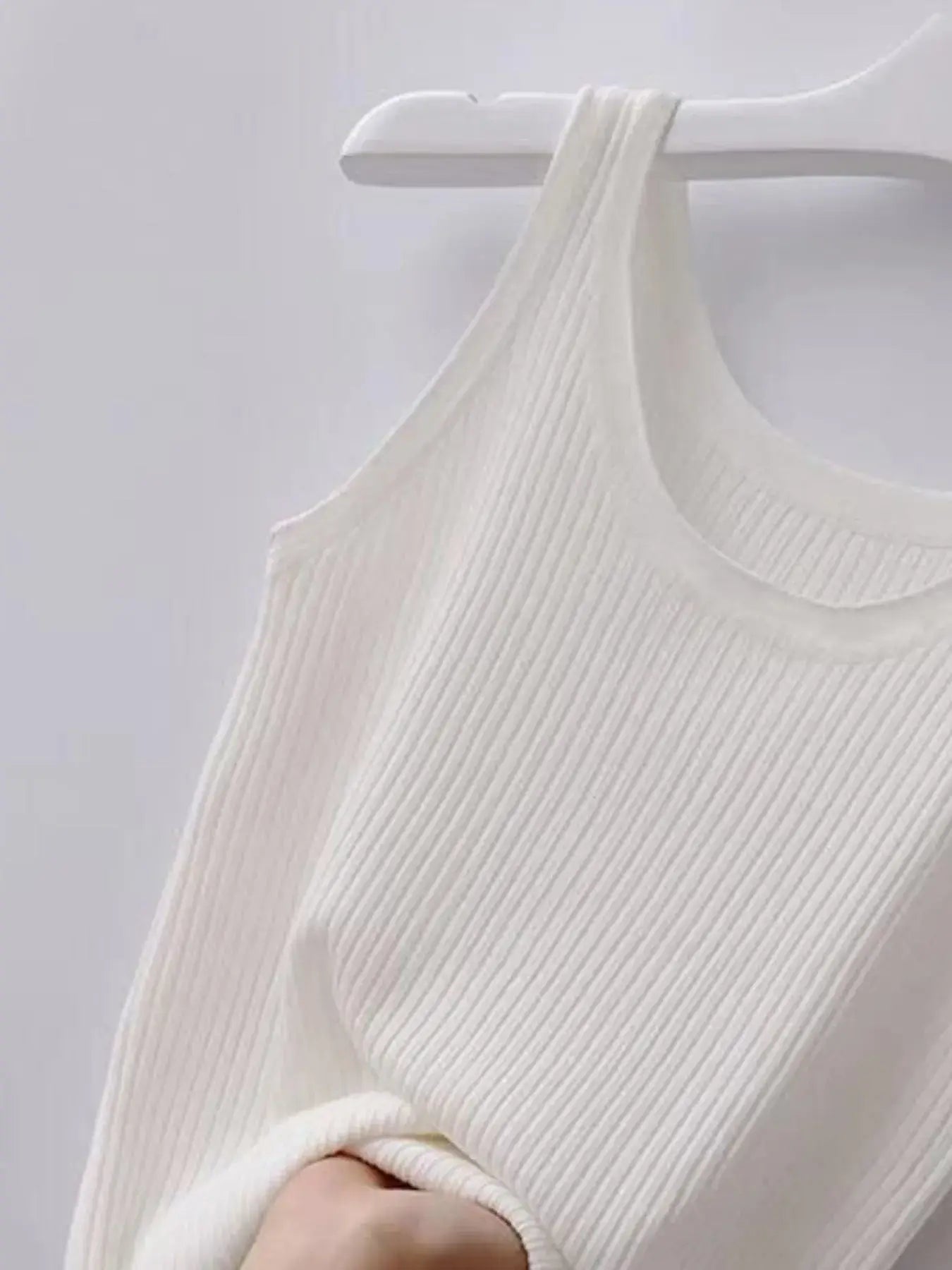 White ribbed tank top on a hanger against a light gray background