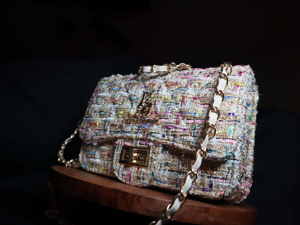 Multicolored tweed handbag with gold chain strap on a dark background