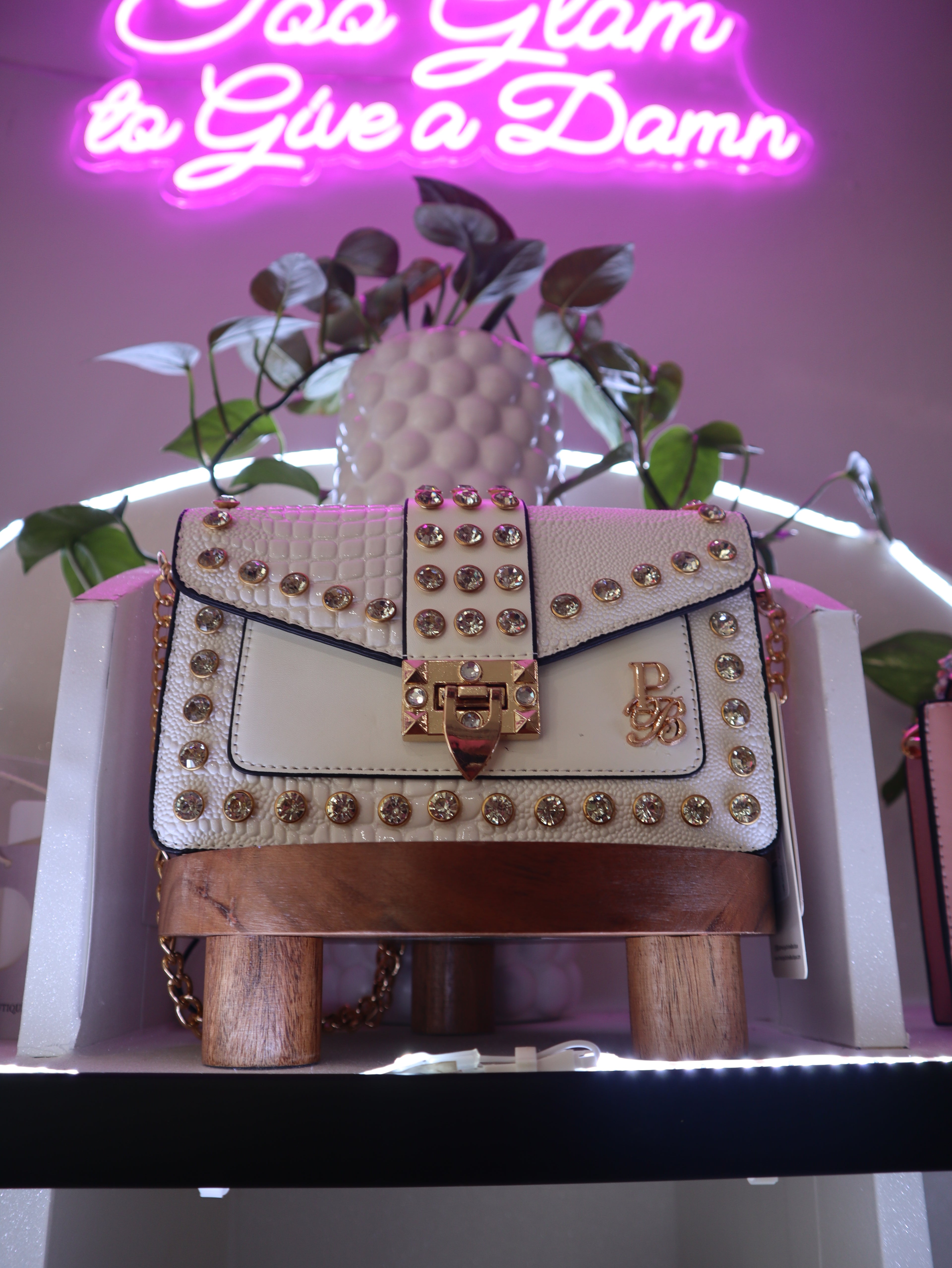 Decorative handbag with gold studs on a shelf with a neon sign in the background