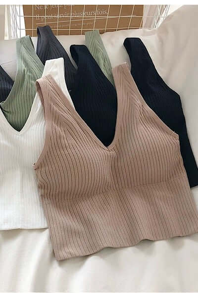 Beige ribbed tank top on a white surface with other clothing items in the background.