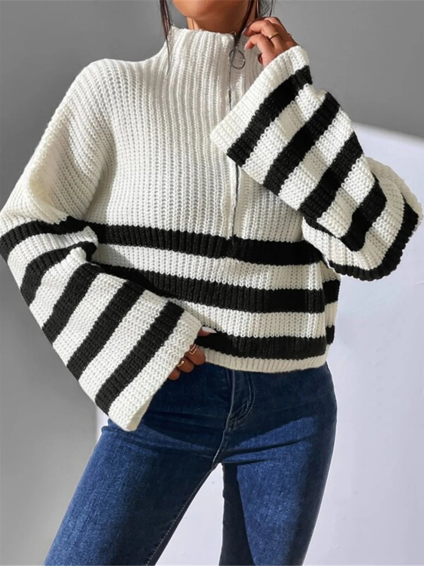White sweater with black stripes worn by a person on a gray background