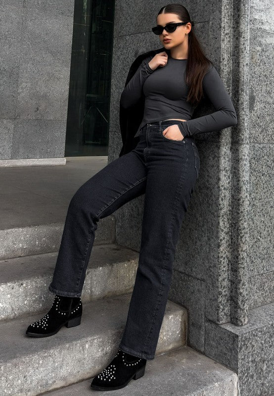 Woman in black outfit leaning against a stone wall