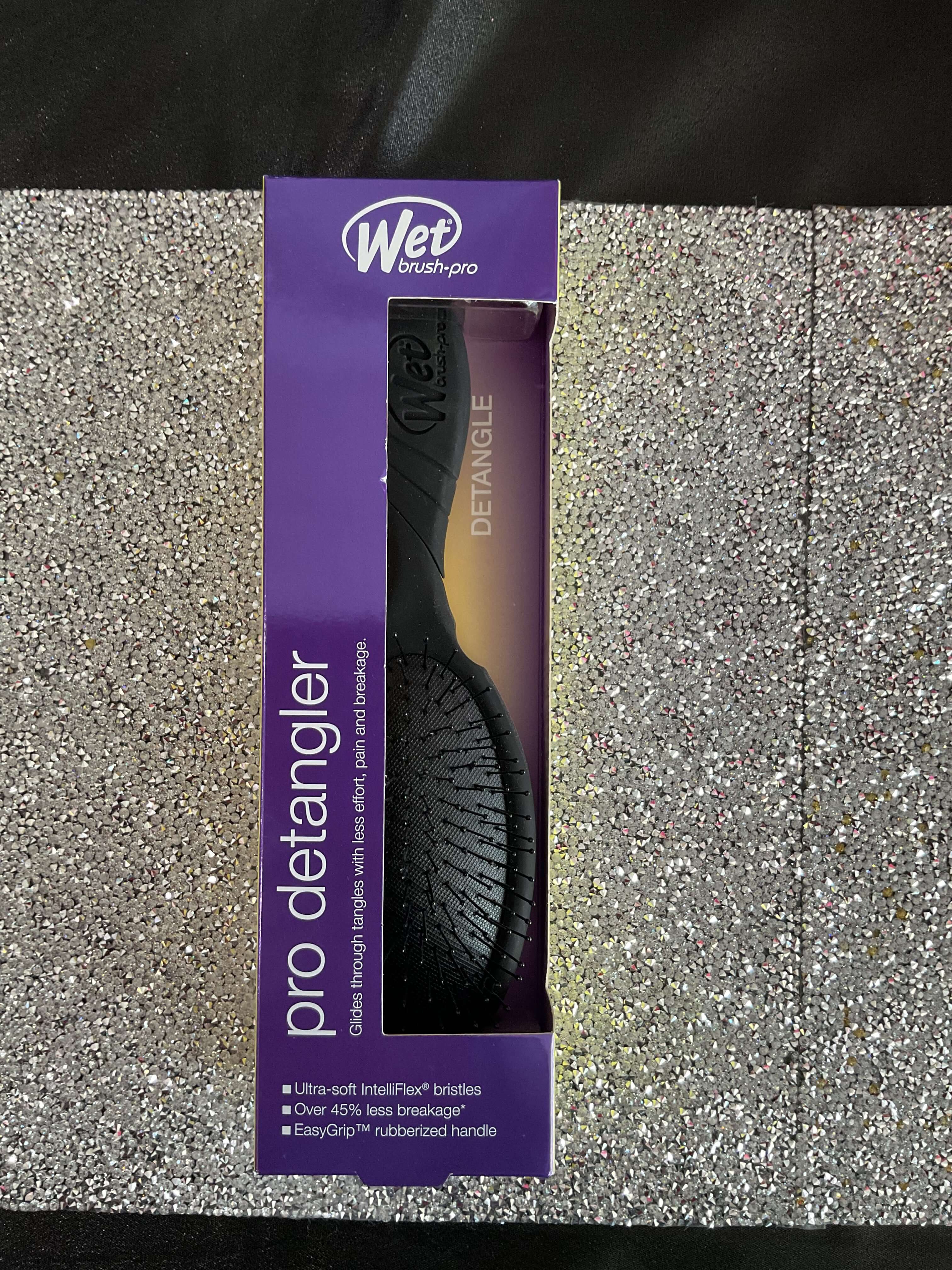 Purple packaging of a Wet Brush Pro Detangler on a textured surface