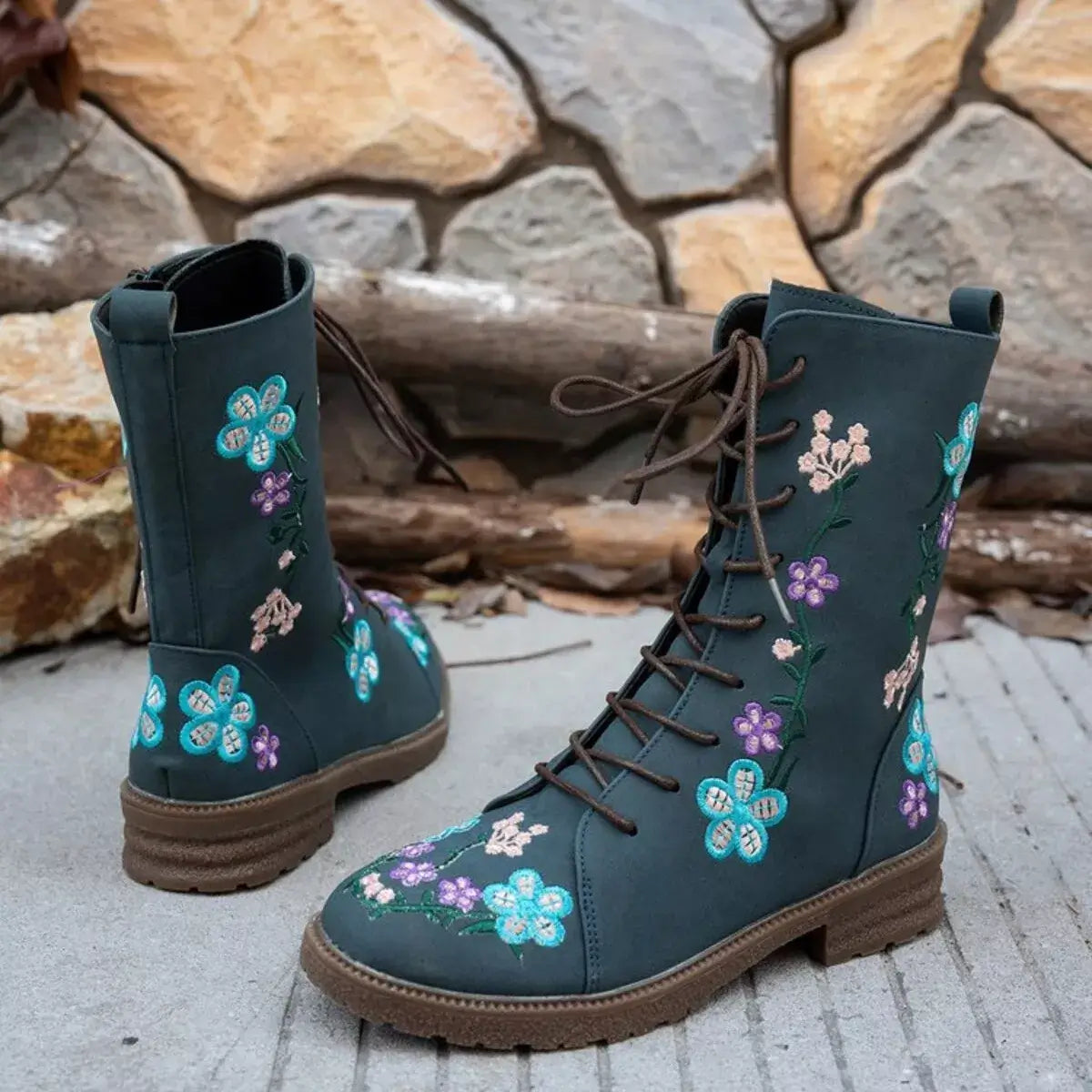 Blue boots with floral embroidery on a stone surface and stone wall background