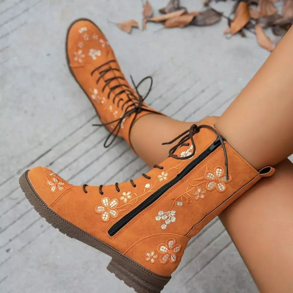 Orange boots with floral embroidery on a light gray surface