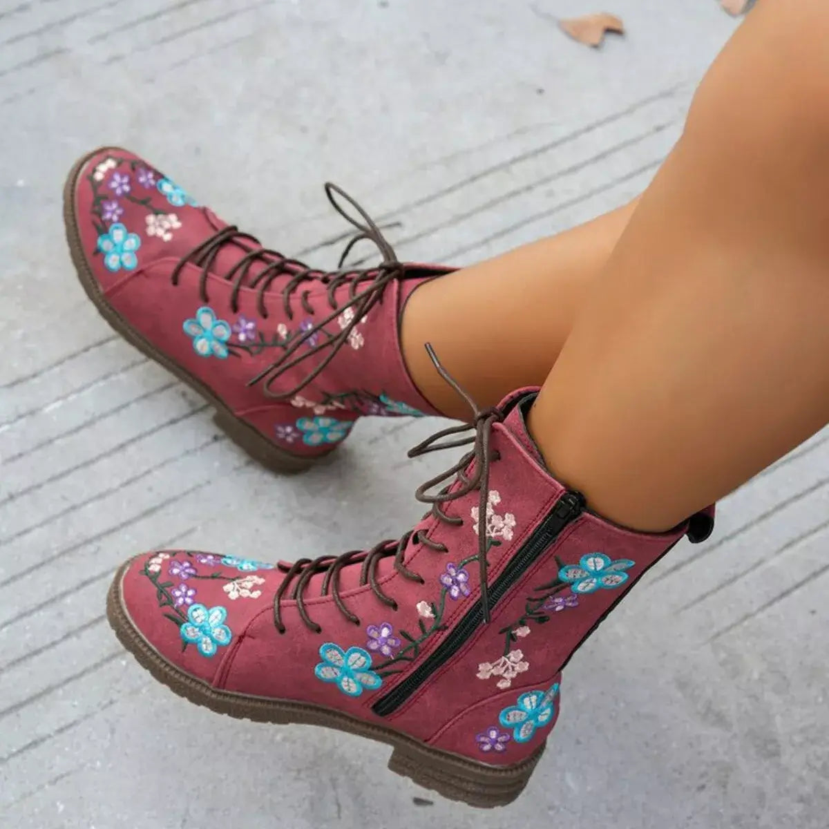 Red floral boots worn on a light gray pavement