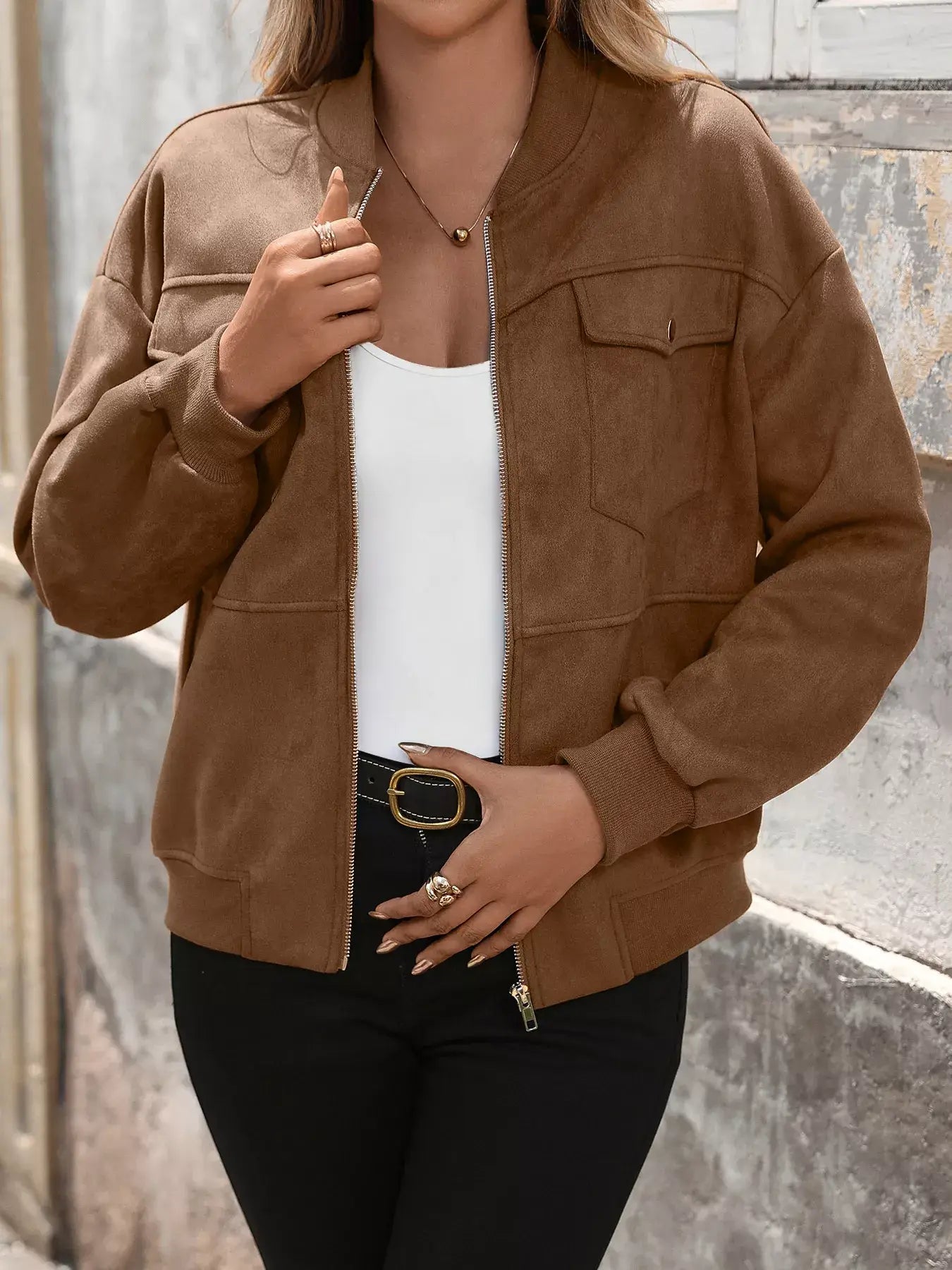 Person wearing a brown suede jacket with a neutral background