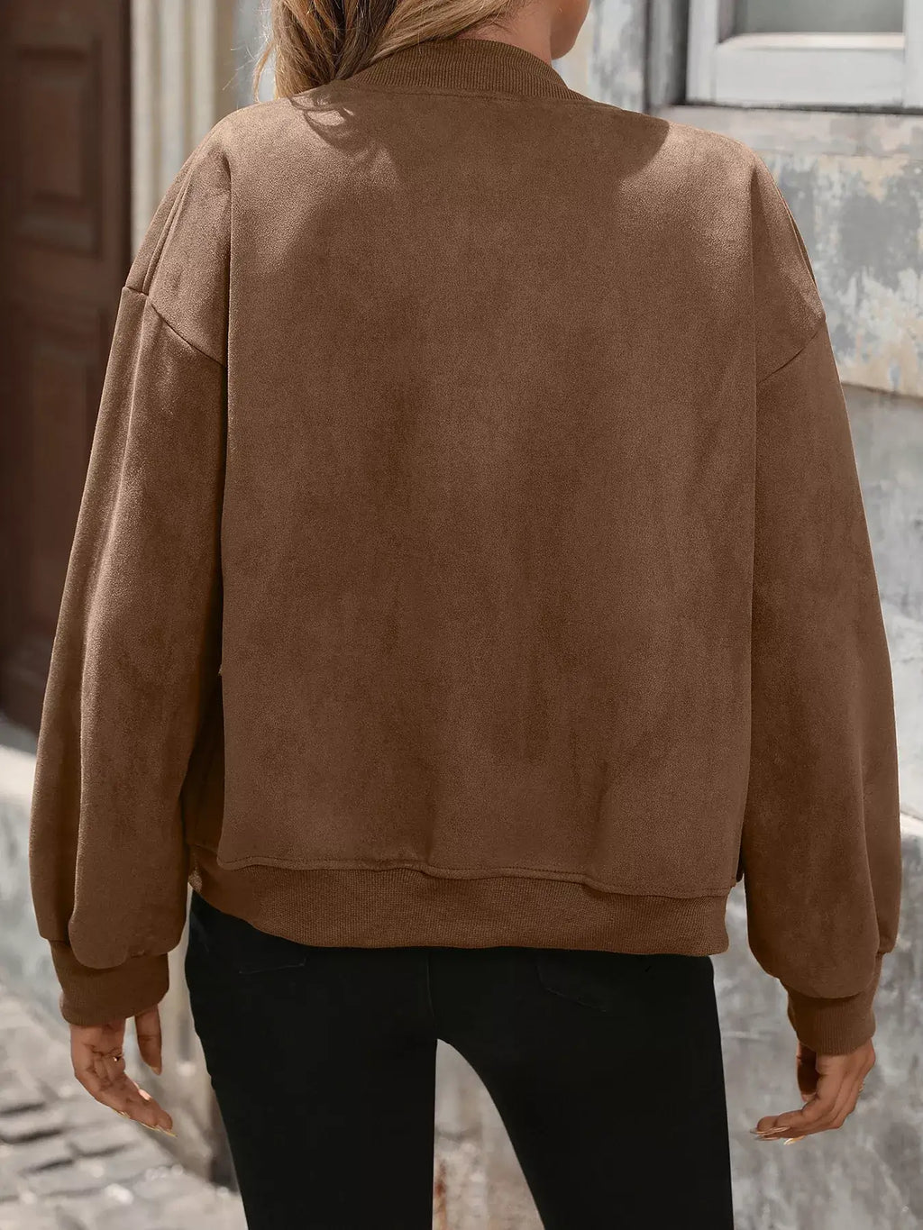 Person wearing a brown suede jacket outdoors.