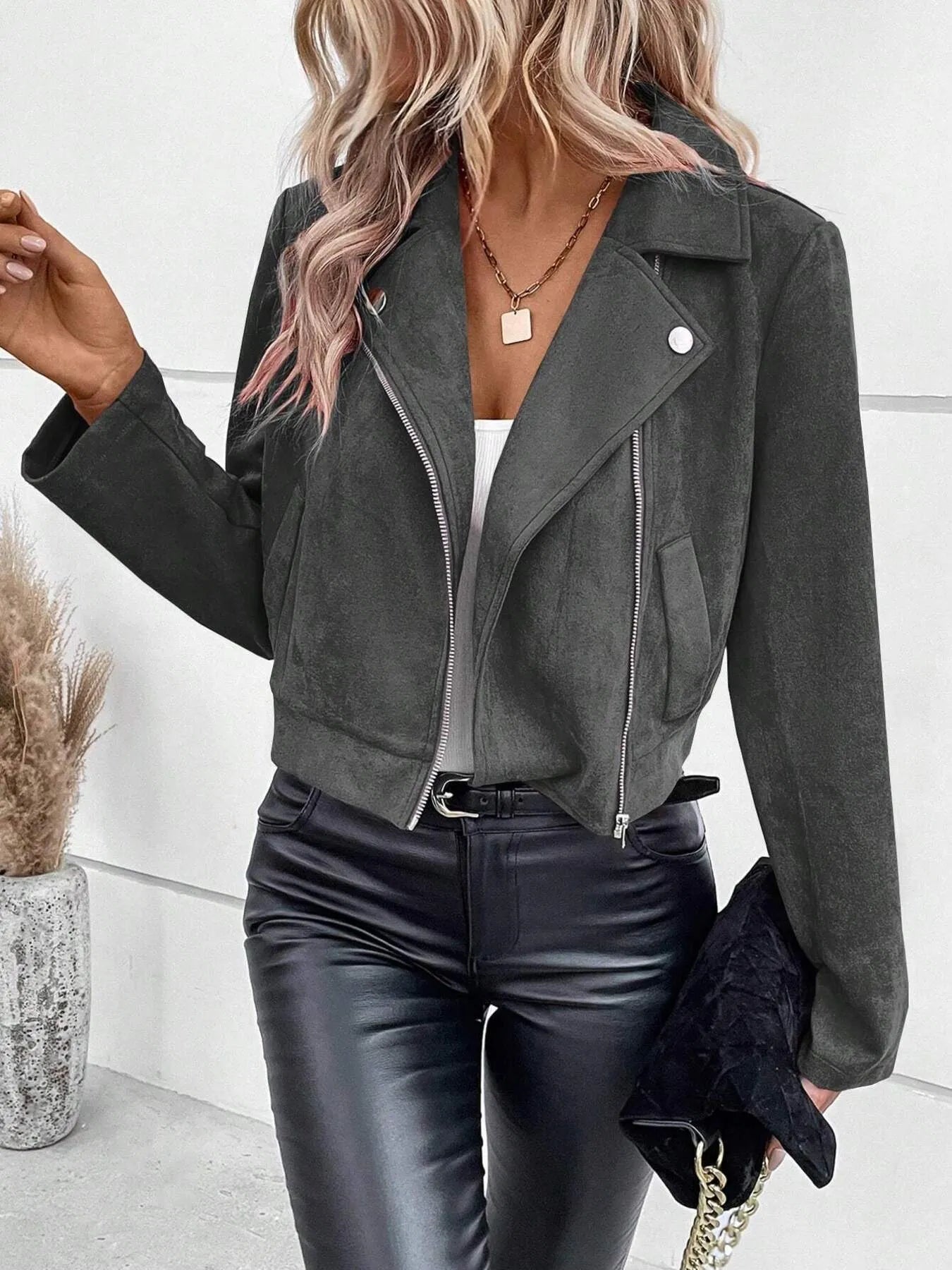 Person wearing a gray suede jacket and black leather pants indoors.