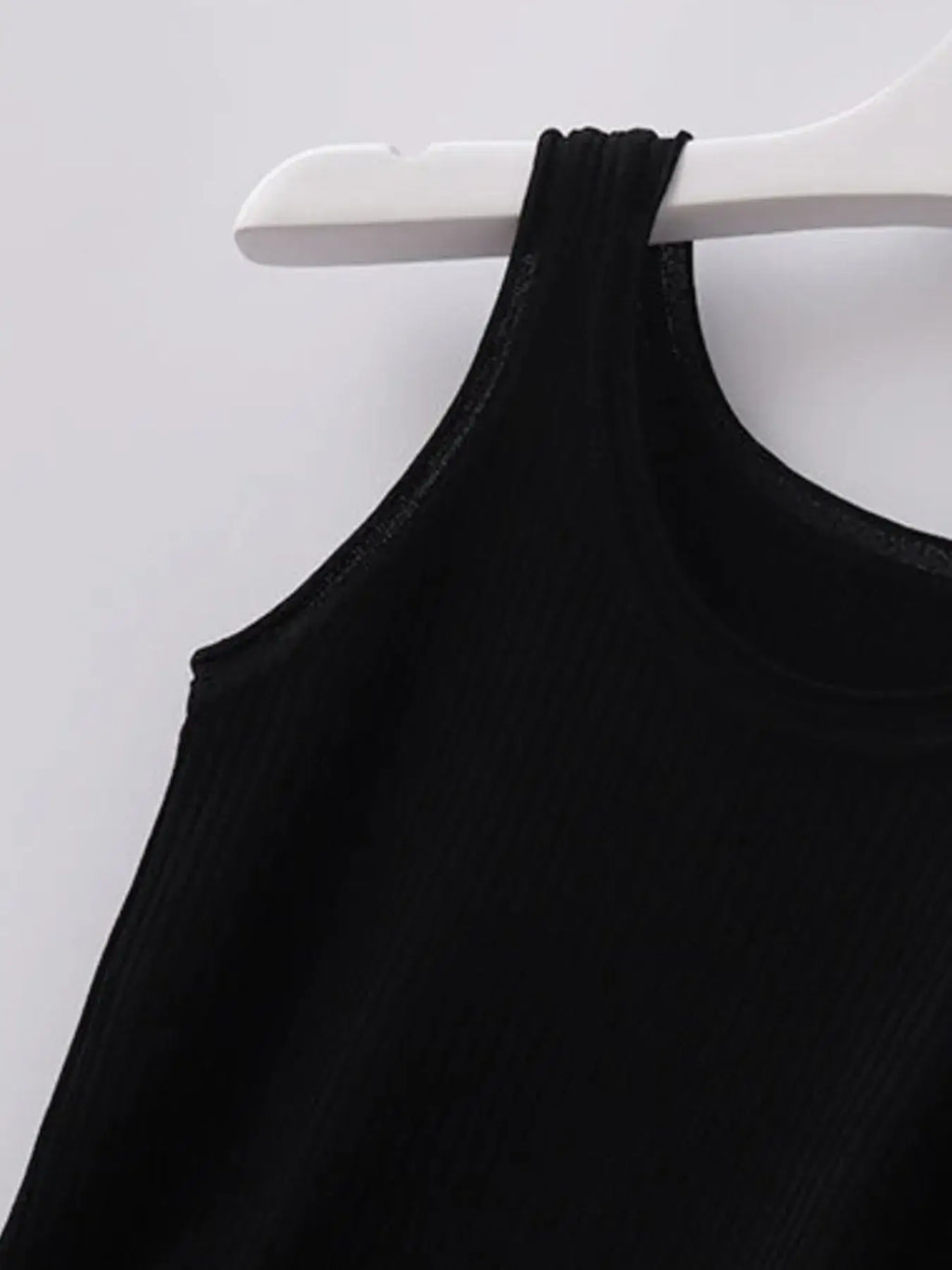 Black tank top on a white hanger against a light gray background