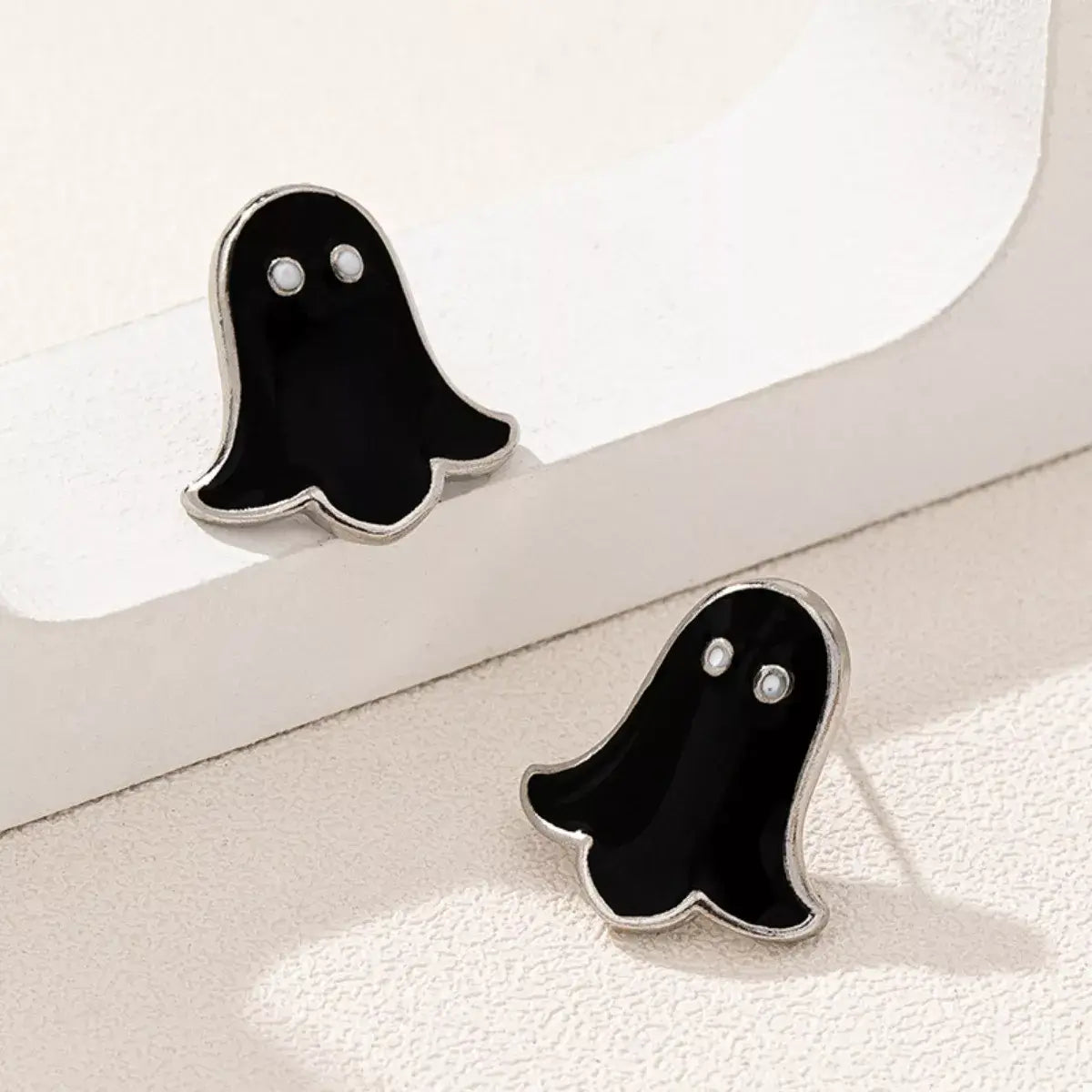 Ghost-shaped earrings on a white surface