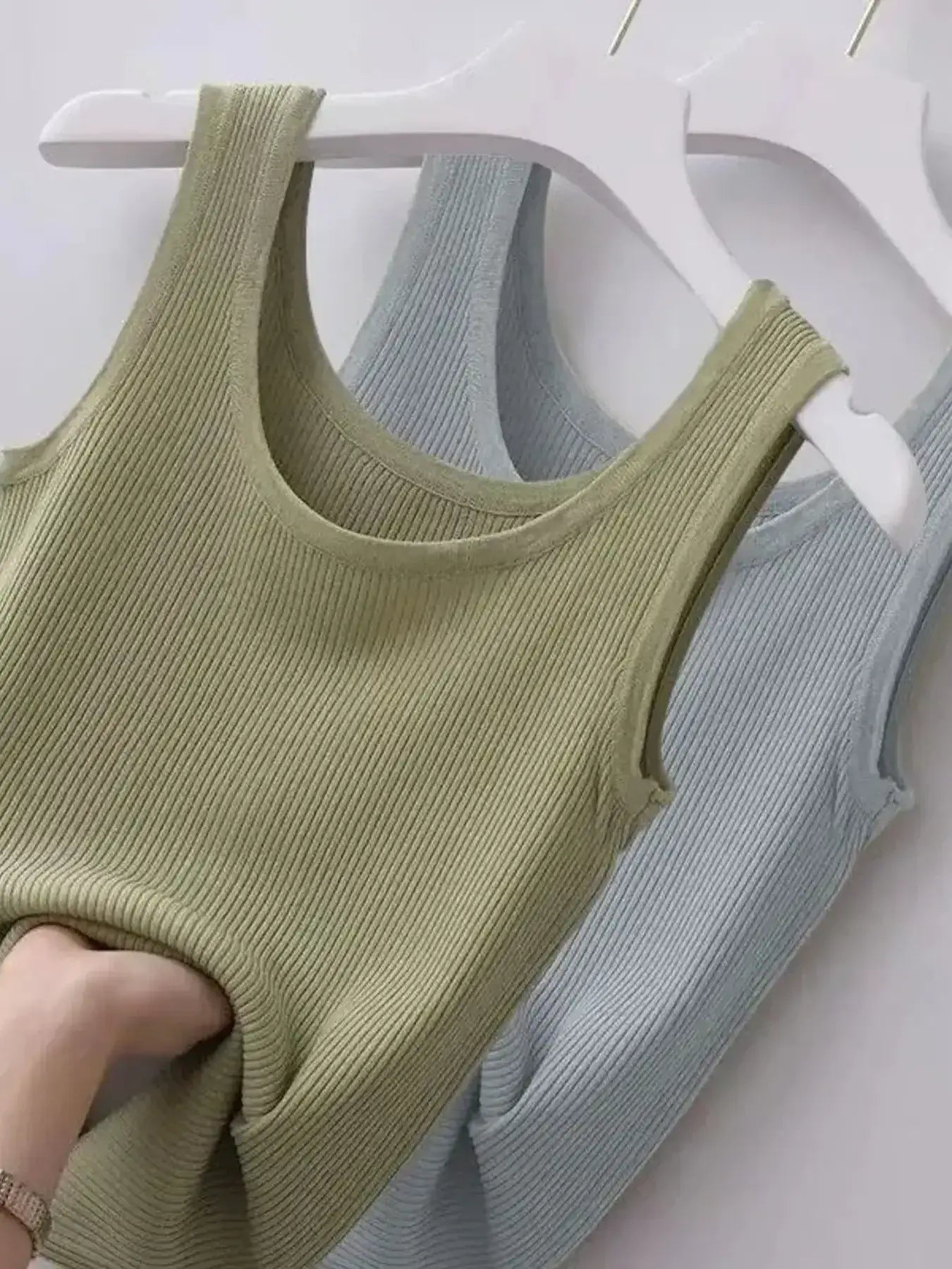 Green tank top on a hanger against a white background