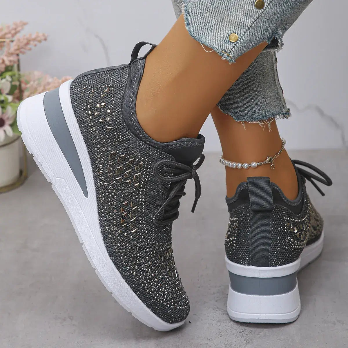 Gray sneakers with rhinestone details worn by a person on a neutral background