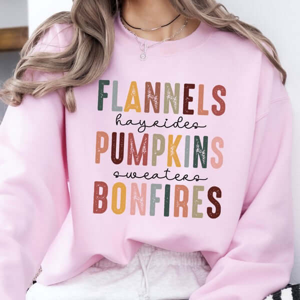 Pink sweatshirt with colorful text design worn by a person.