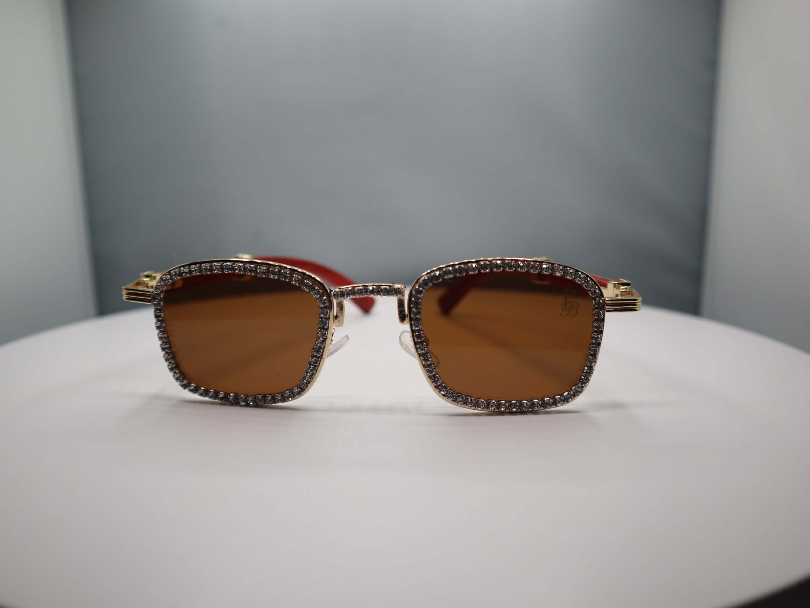 Total Gem women's sunglasses with rhinestone detailing and brown lenses on a display.