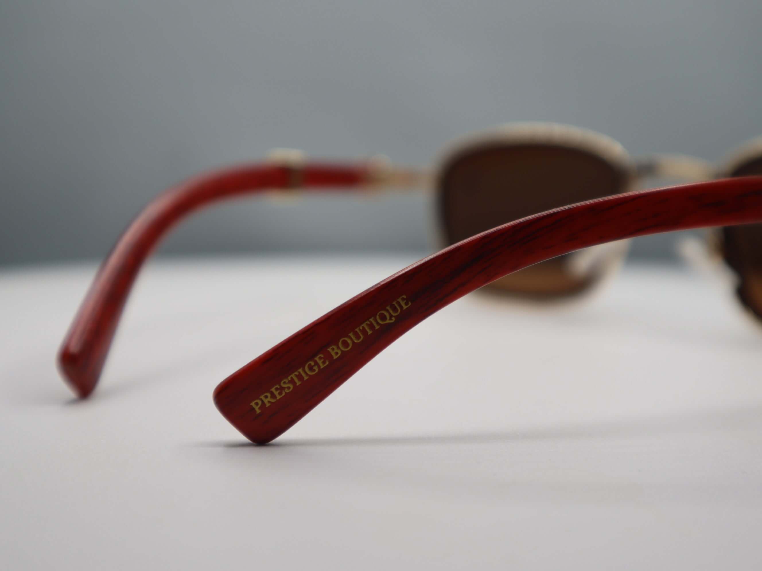 Close-up of Prestige Boutique rhinestone women's sunglasses with stylish red frames.