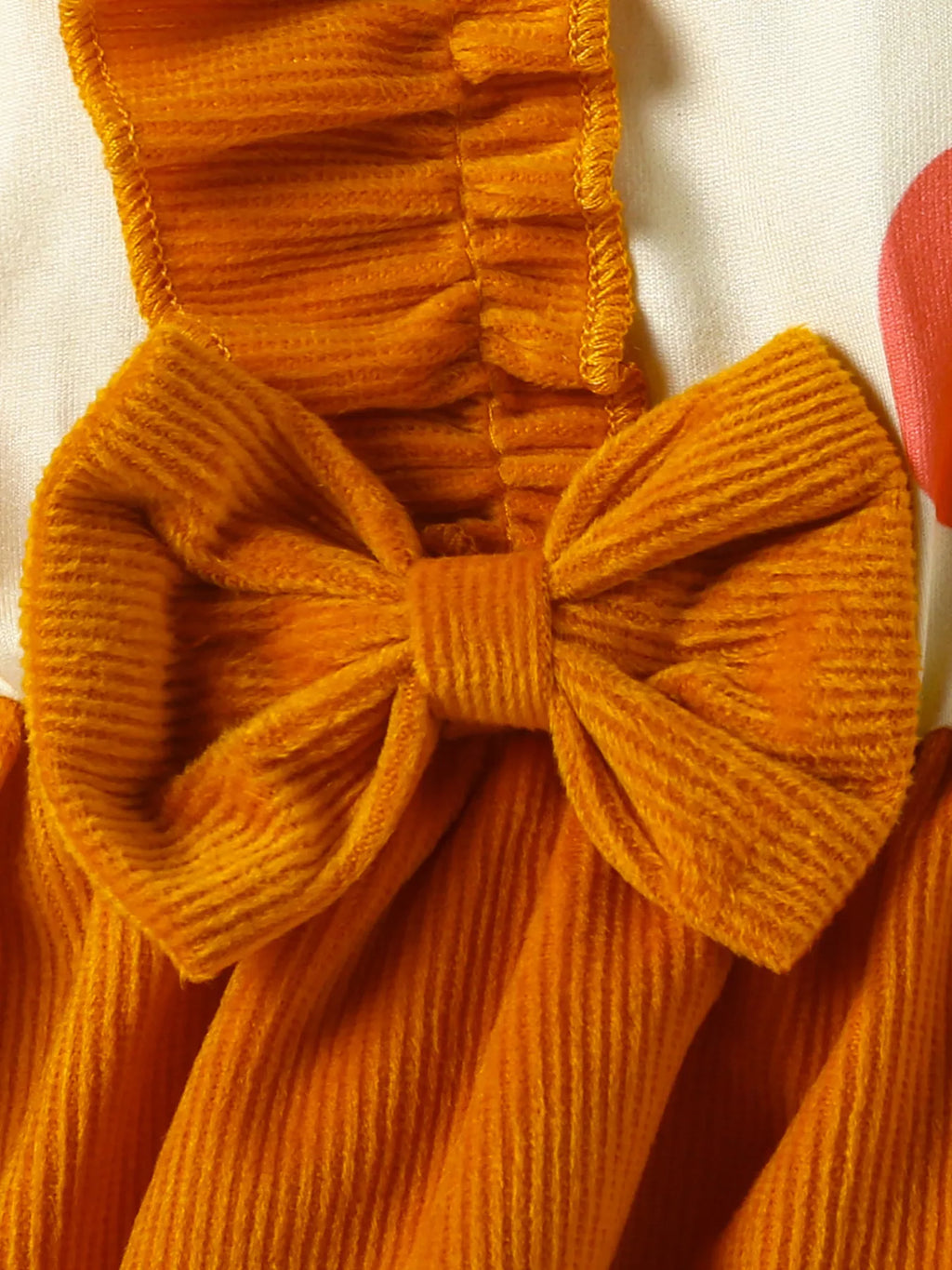 Close-up of an orange textured garment with a bow detail on a white background