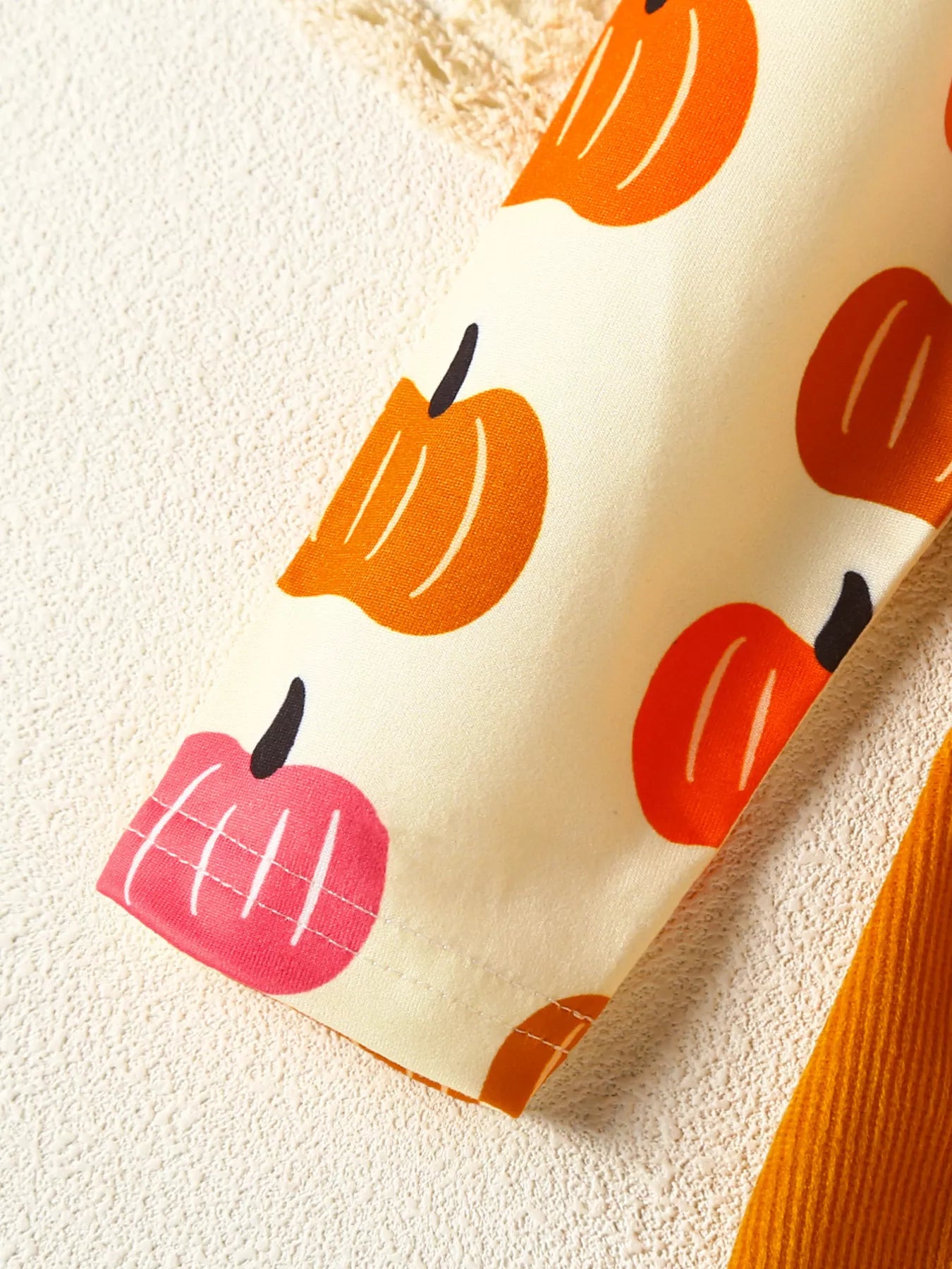 Fabric with colorful apple pattern on a textured beige background