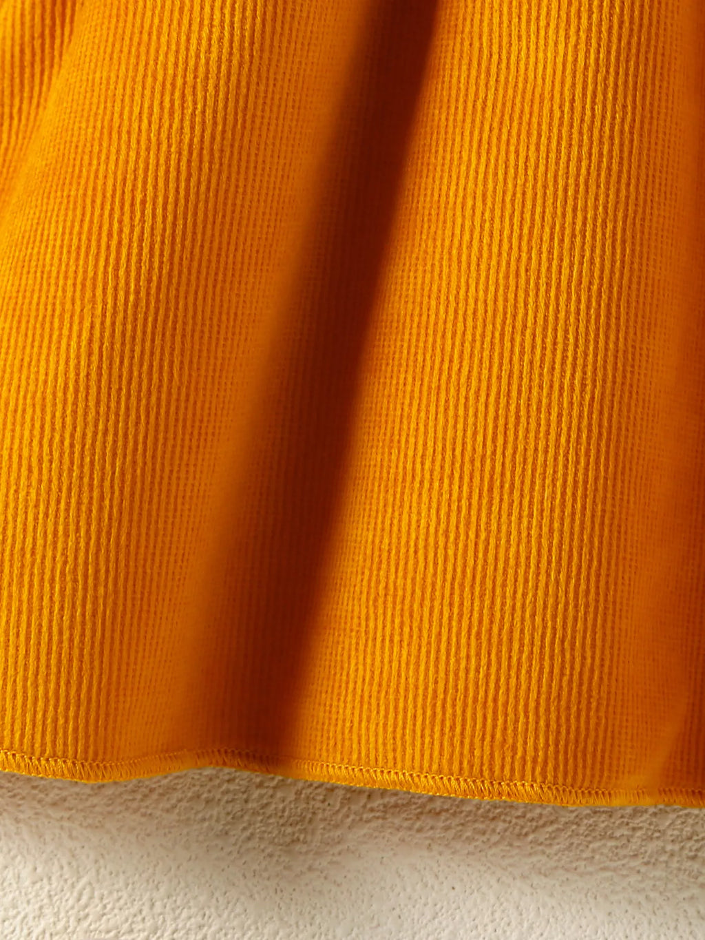 Close-up of orange fabric texture on a beige background