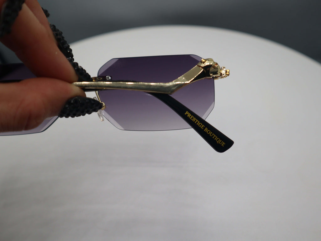 Close-up of Prestige Boutique Queen Of The Jungle sunglasses with purple beveled lenses and unique frame design.