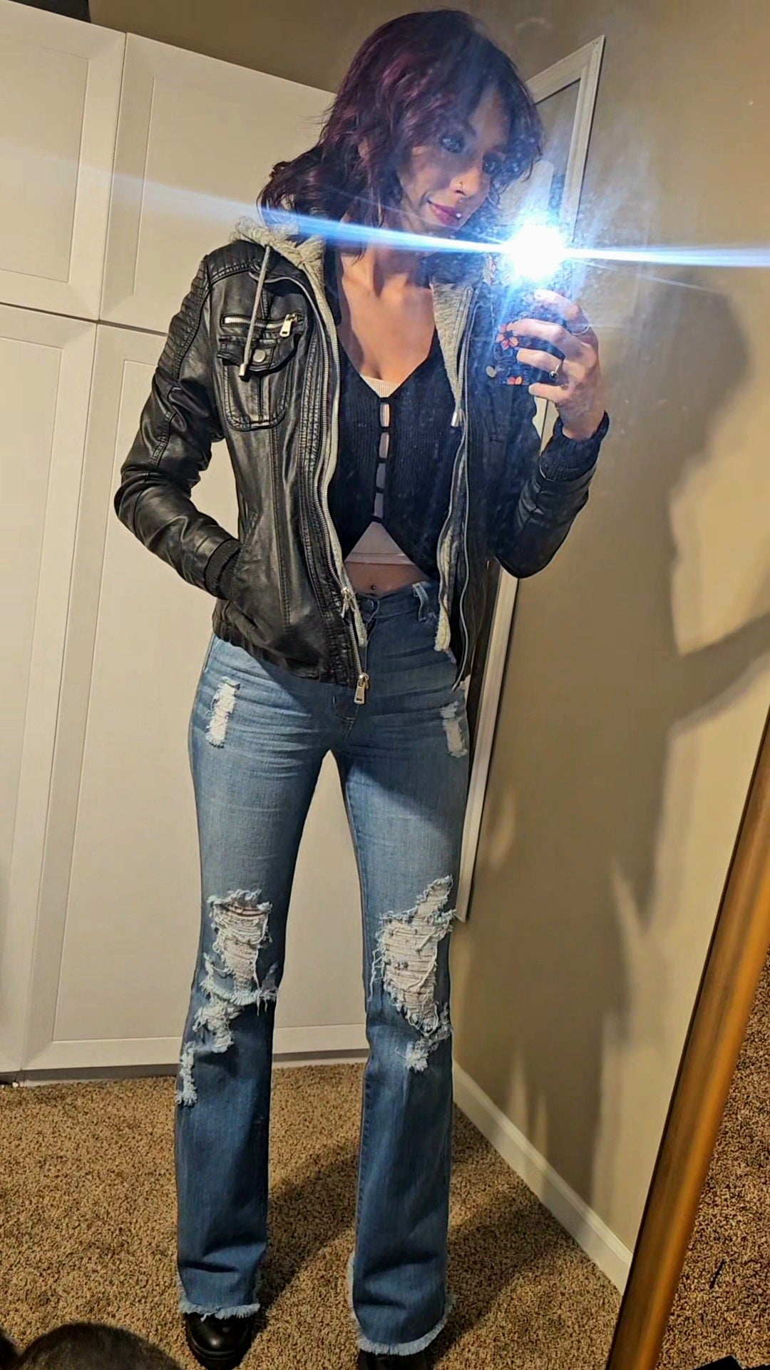 Woman wearing Premium USA Denim Bootcut High Rise Jeans and a leather jacket in a mirror selfie.