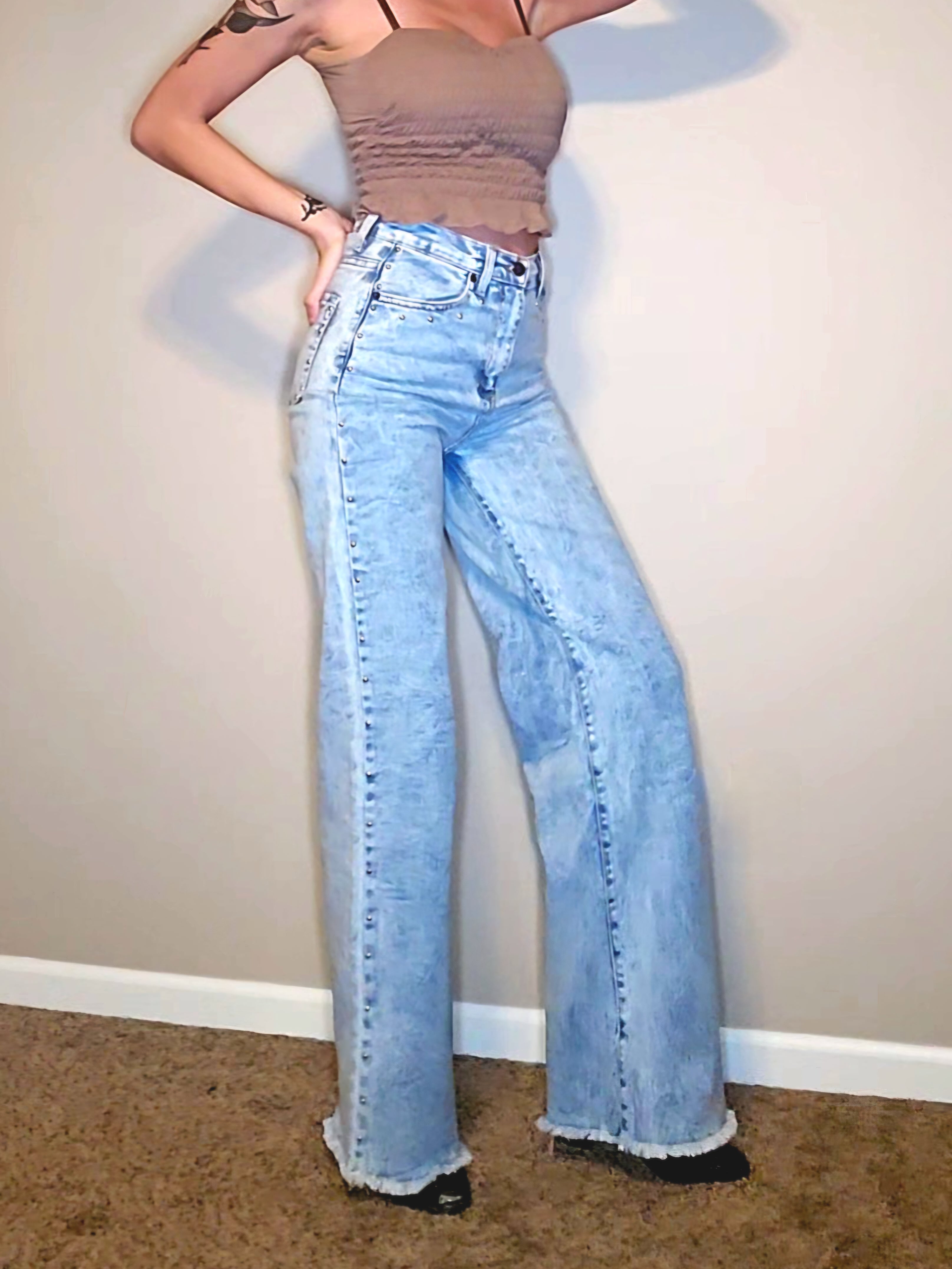 Brooklyn Studded BootCut High Rise Jeans showcasing a tall model in light wash denim with frayed hem and studded detail.