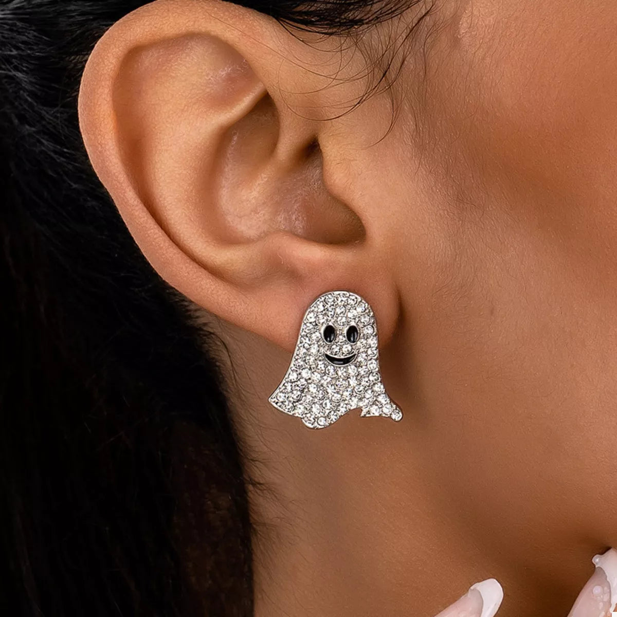 Ghost-shaped earring worn on an ear with a blurred background