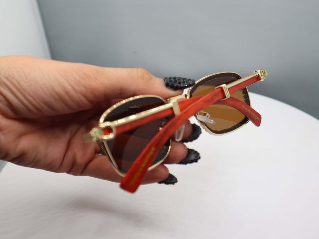 Hand holding Total Gem women's sunglasses featuring red arms and rhinestone details, showcasing chic style and UV protection.