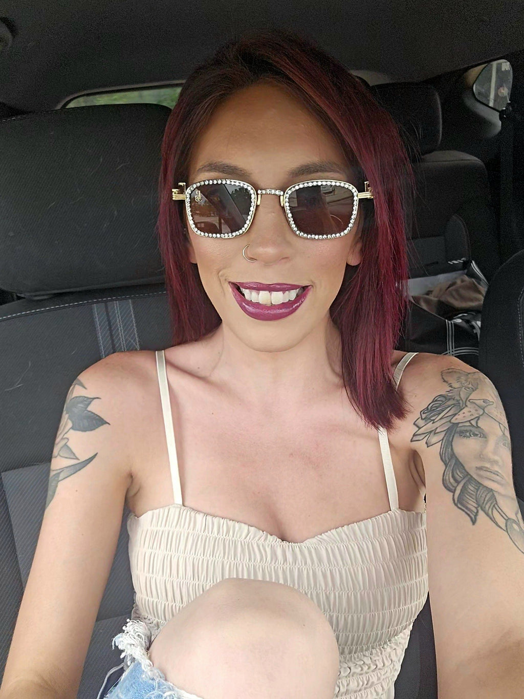 Woman with tattoos and sunglasses sitting inside a vehicle