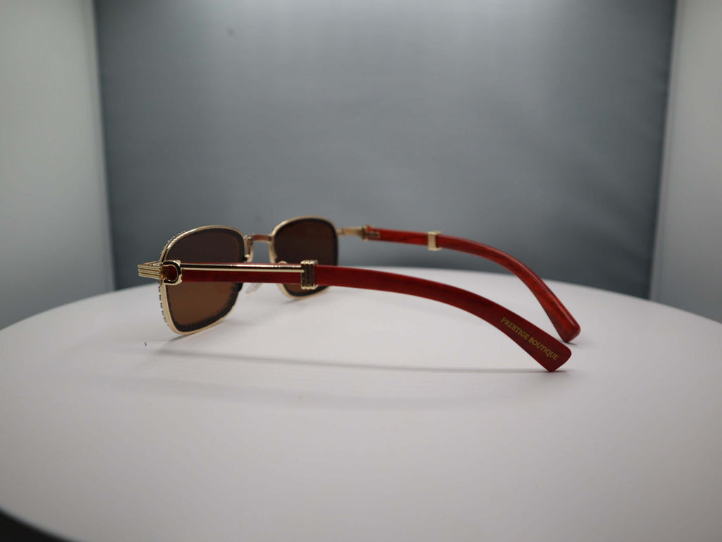 Side view of women's rhinestone sunglasses with stylish gold frame and red arms on a white display.