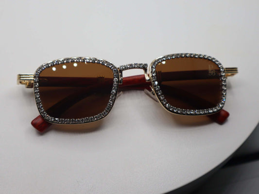 Stylish women's rhinestone sunglasses with brown lenses and gold detailing on a round display.
